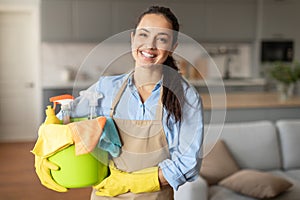 Smiling woman ready with bucket of cleaning supplies