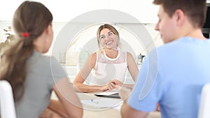 Smiling woman realtor discussing home choice with couple in real estate agency office, offering various options for