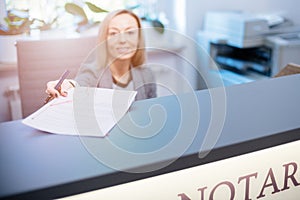 Smiling woman at the reception desk, office, notary office gives documents for signature