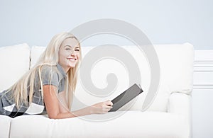 Smiling Woman Reclining on Couch With Book