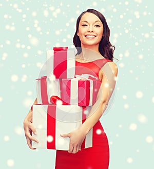 Smiling woman in red dress with many gift boxes