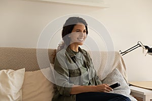 Smiling woman relax on sofa watching TV