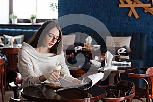 A smiling woman in a restaurant with the menu in hands