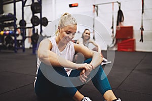 Smiling woman resting on a gym floor after a workout