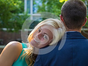 Smiling woman resting her head on the shoulder of a man under the sunlight