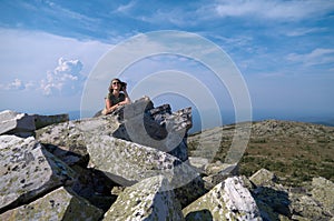 Smiling woman resting on top of cliff after climbing