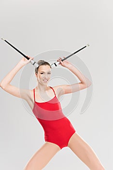 Smiling woman rhythmic gymnast holding clubs