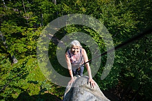 Smiling woman rockclimber is reaching top of the rock