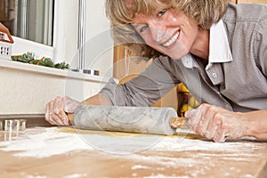Smiling woman rolling dough