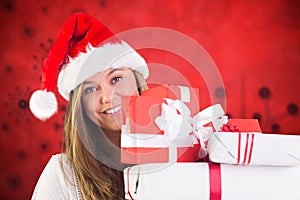 Smiling woman in santa costume holding stack of christmas gifts