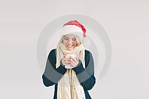 Smiling woman in Santa hat with cup of coffee, isolated on white. The girl is dressed in sweater, christmas cap and