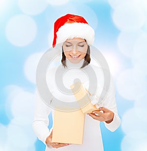 Smiling woman in santa helper hat opening gift box