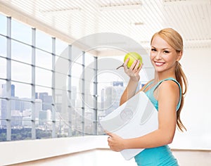 Smiling woman with scale and green apple in gym