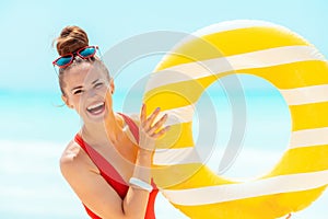 Smiling woman on seacoast showing yellow inflatable lifebuoy