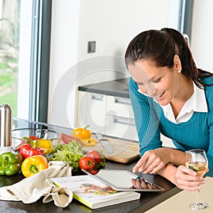 Smiling woman searching recipe tablet kitchen vegetables