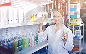 Smiling woman seller advising on pet shampoo