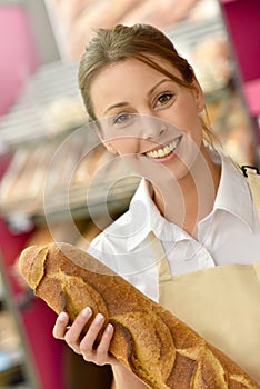 Smiling woman selling fresh bread in bakery shop