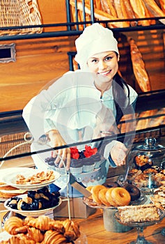 Smiling woman selling fresh pastry and loaves