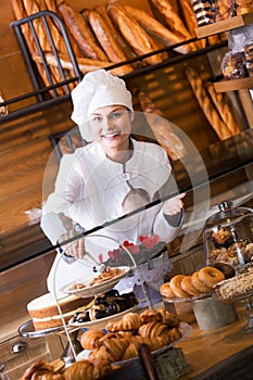 Smiling woman selling fresh pastry and loaves