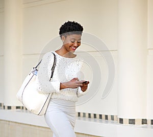 Smiling woman sending text message on mobile phone