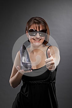 Smiling woman with shoe posing thumbs up