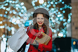 Smiling woman shopper outdoors in city street in evening