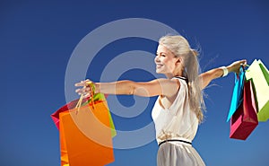 Smiling woman with shopping bag rising hands