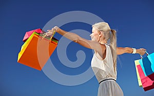 Smiling woman with shopping bag rising hands