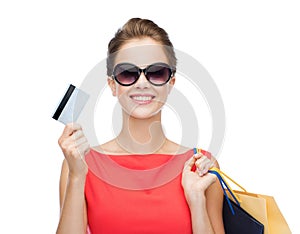 Smiling woman with shopping bags and plastic card