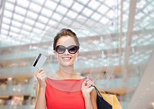 Smiling woman with shopping bags and plastic card