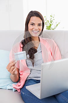 Smiling woman shopping online through laptop using credit card
