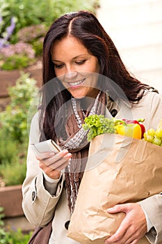 Smiling woman shopping vegetables mobile phone sms