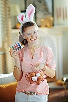 Smiling woman showing basket with eggs and food coloring