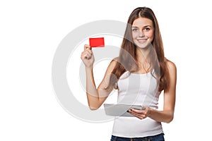 Smiling woman showing blank credit card hold tablet pc in hand, in white t-shirt, isolated over gray background