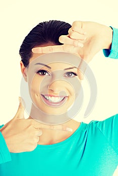 Smiling woman is showing frame by hands.