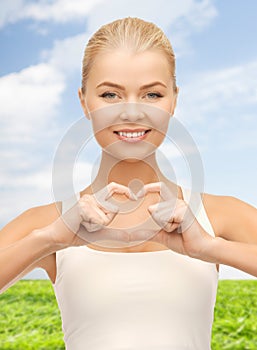 Smiling woman showing heart shape gesture
