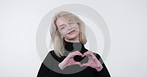 Smiling woman showing heart shape by hand on White background