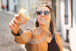 Smiling woman showing and pointing an ice cream cone at camera.