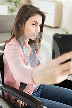 smiling woman sititng in wheelchair while making selfies