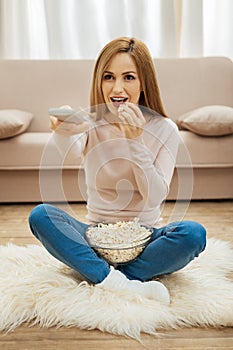 Smiling woman sitting on the carpet with popcorn