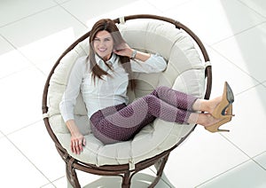 Smiling woman sitting in comfortable round chair