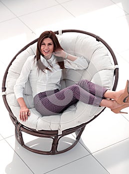 Smiling woman sitting in comfortable round chair