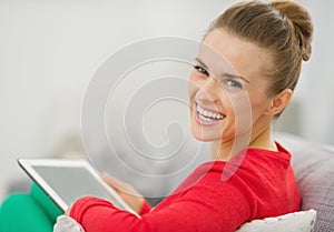 Smiling woman sitting on couch and using tablet pc