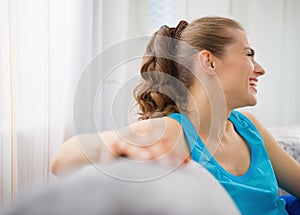 Smiling woman sitting on divan in living room
