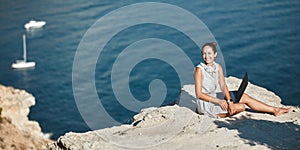 Smiling woman sitting on high hill with laptop. Work from any place. Freelance job and remote office idea, copy space