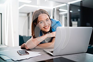 Smiling woman sitting in the kitchen and using the laptop. Working from home in quarantine lockdown. Social distancing