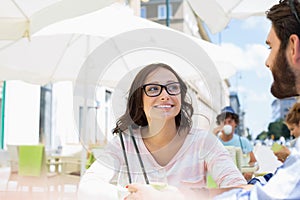 Smiling woman sitting with man at sidewalk cafe