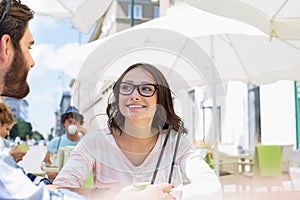 Smiling woman sitting with man at sidewalk cafe