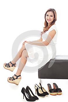 smiling woman sitting next to pairs of shoes