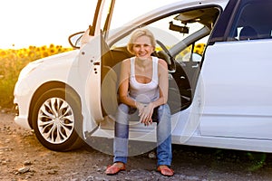 Smiling woman sitting in the open door of her car